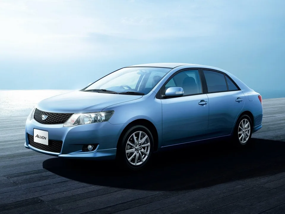 Toyota Allion второго поколения T260, голубой седан, вид спереди-сбоку слева, легкосплавные диски, фон — море
