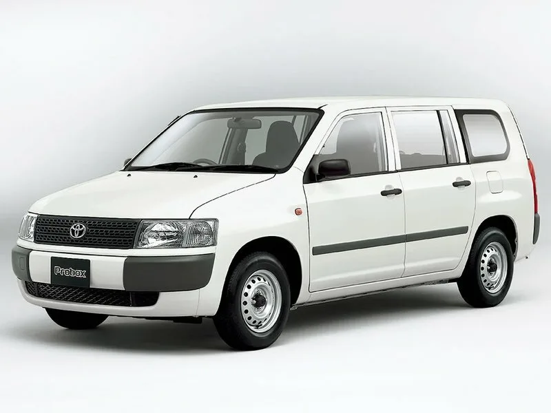 Toyota Probox первых лет выпуска, белый фургон, вид спереди-сбоку слева, стальные диски без колпаков, чёрные неокрашенные бамперы