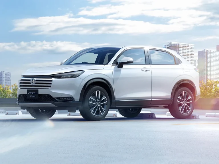 Honda Vezel e:HEV второго поколения после обновления 2024 года, белый кроссовер на крыше паркинга, вид спереди-сбоку