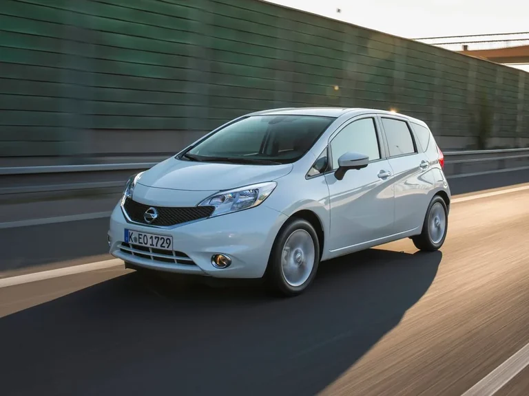 Nissan Note второго поколения E12 2012&ndash;2016 годов, белый хэтчбек в движении по автомагистрали, вид спереди-сбоку