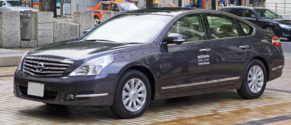 Nissan Teana второго поколения J32, тёмно-серый седан спереди-сбоку слева на городской улице в Японии