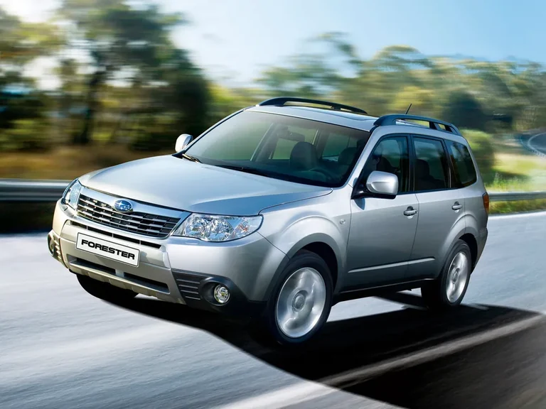 Subaru Forester третьего поколения, серебристый кузов с рейлингами в движении, табличка FORESTER на бампере