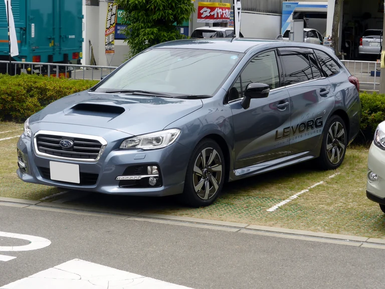 Subaru Levorg первого поколения VM, серо-голубой универсал с воздухозаборником на капоте, вид спереди-сбоку на парковке в Японии, надпись LEVORG на борту