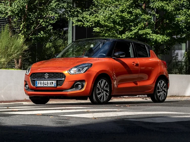 Suzuki Swift после обновления 2020 года, оранжевый хэтчбек с чёрной крышей и французским номером на пешеходном переходе
