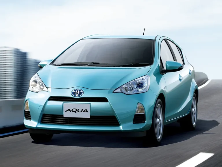Toyota Aqua первого поколения NHP10, голубой хэтчбек в движении, вид спереди-сбоку