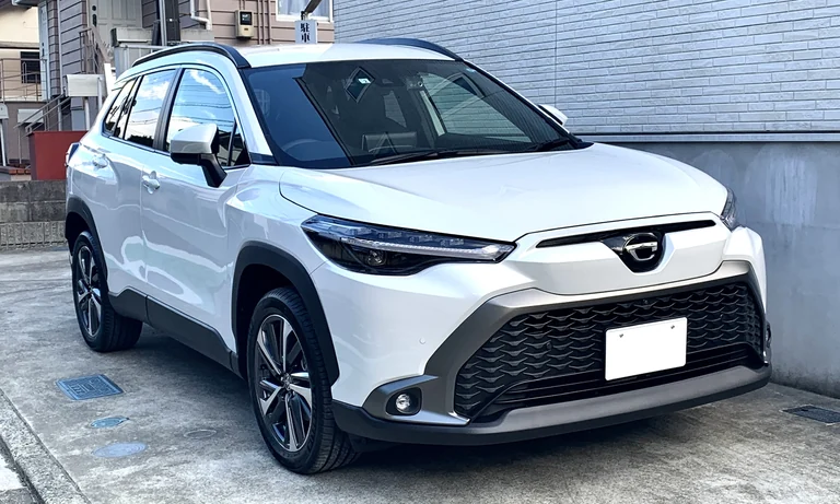 Toyota Corolla Cross Z 2022 года, японская запись, белый кроссовер, вид спереди-сбоку