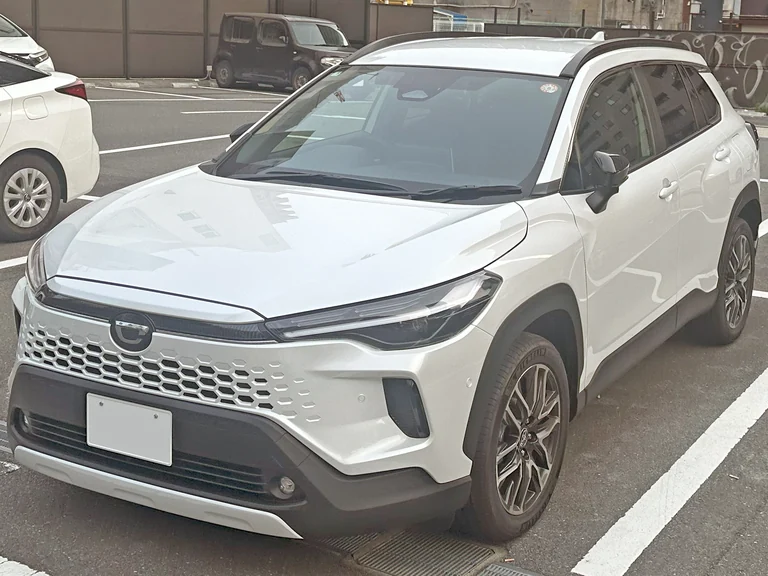 Toyota Corolla Cross Z после обновления 2025 года, белый кроссовер с новой передней частью, вид спереди-сбоку