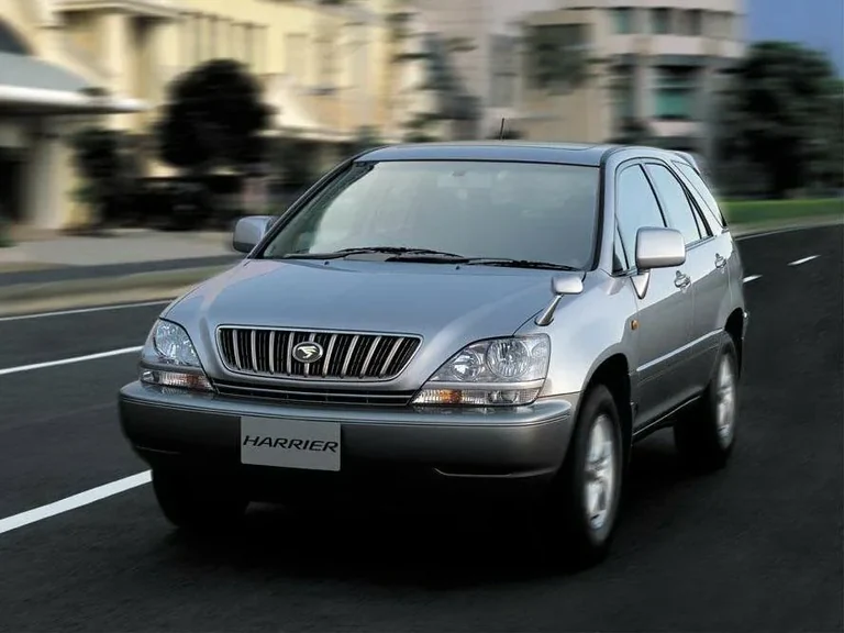 Toyota Harrier первого поколения, серебристый кузов, вид спереди-сбоку, табличка HARRIER на месте номера