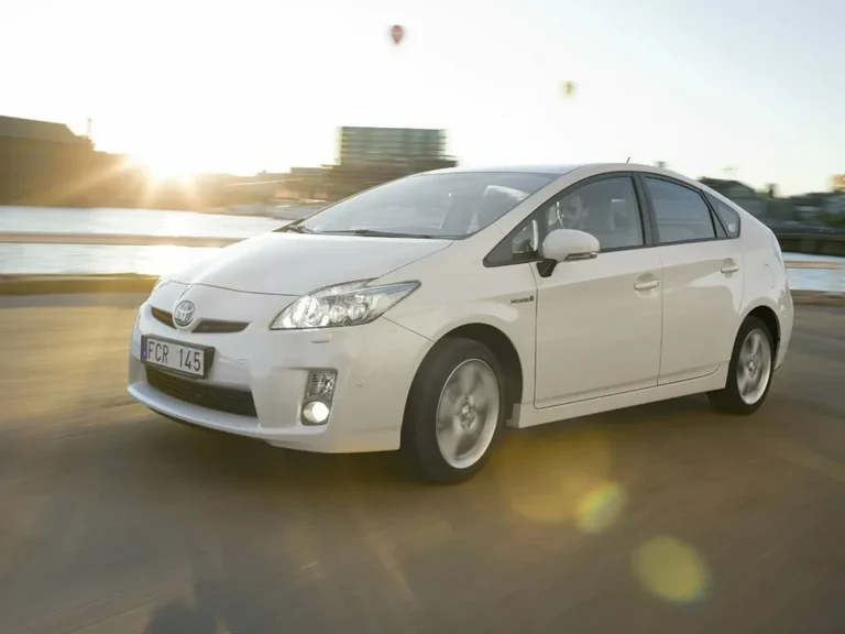 Toyota Prius ZVW30 третьего поколения, белый лифтбек в движении, вид спереди-сбоку