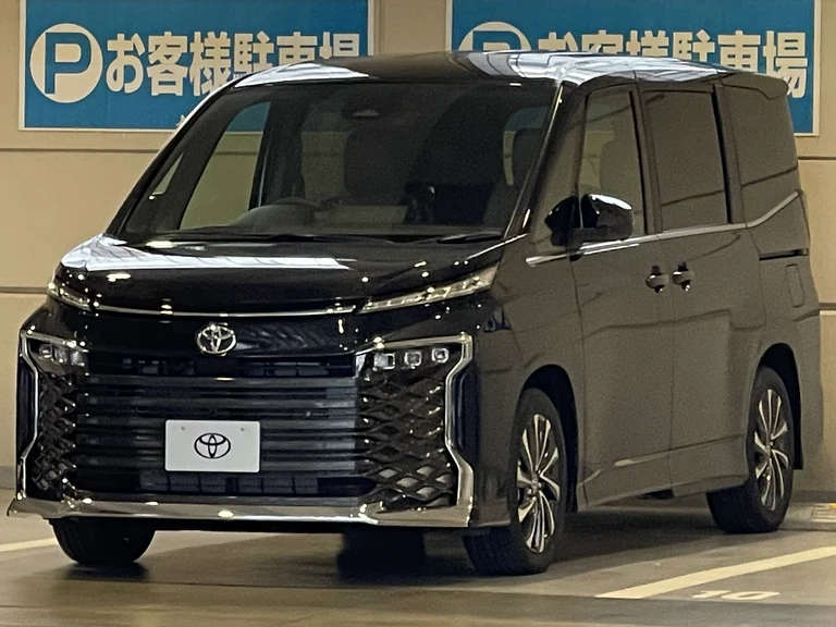 Чёрный Toyota Voxy четвёртого поколения (R90) на крытой парковке, вид спереди-сбоку, крупная тёмная решётка радиатора