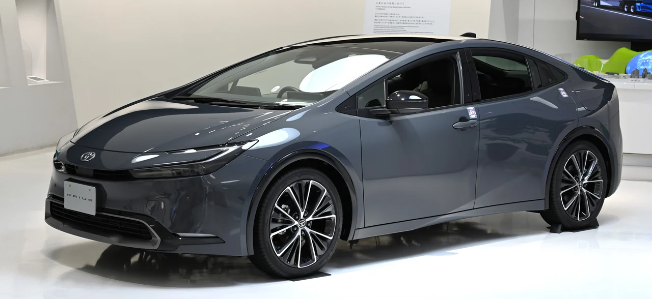 Toyota Prius Z HEV пятого поколения (XW60), тёмно-серый лифтбек на японском стенде, вид спереди-сбоку
